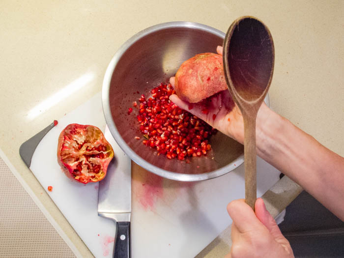 Hold a pomegranate half, seed side down, over a bowl and whack it several times to remove seeds