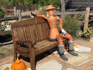 pot person sculpture sitting on garden bench